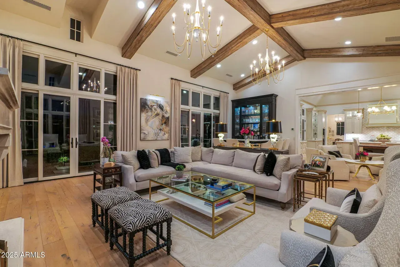 Luxurious living room with light wood floors, large windows, and neutral-toned furniture.