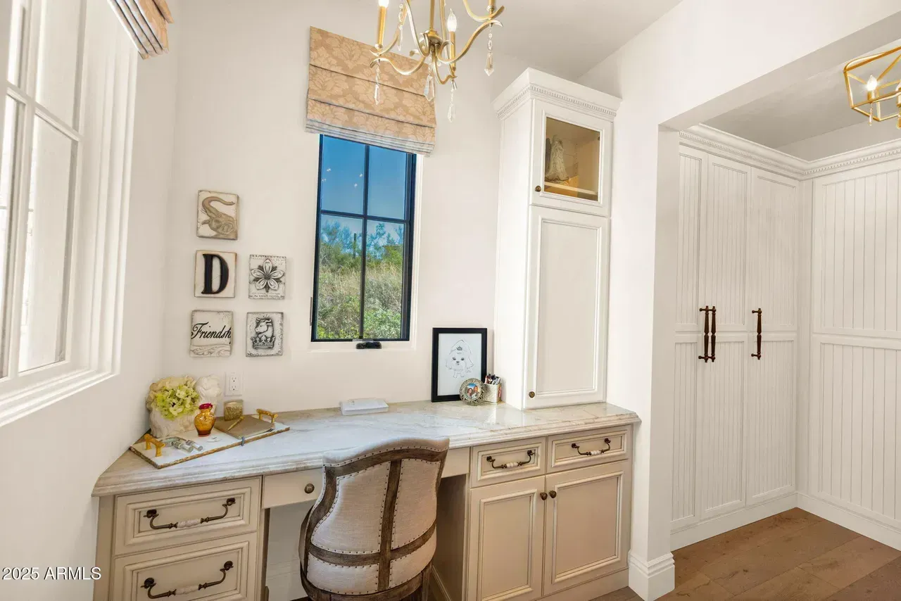Home office with desk, chair, window, built-in cabinets, and a chandelier.