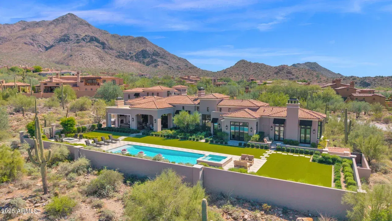 Luxury home with pool and mountain backdrop in desert landscape.