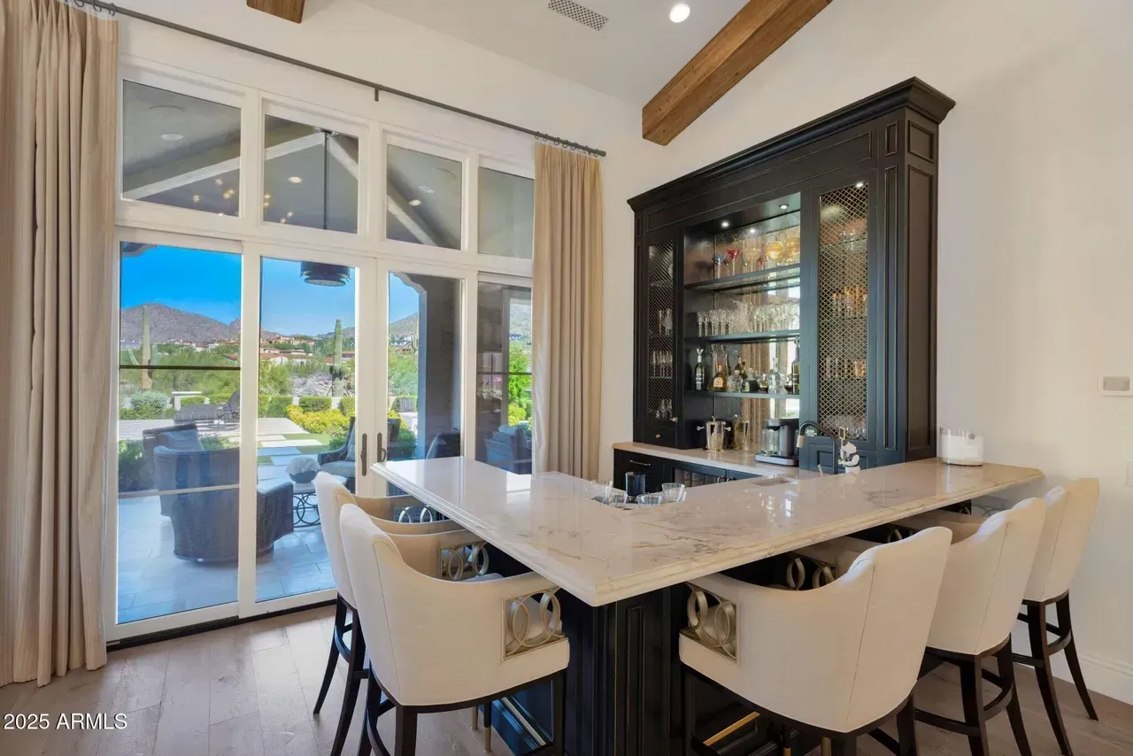 Bar area with a counter, stools, and built-in cabinet, overlooking an outdoor patio and mountain views.