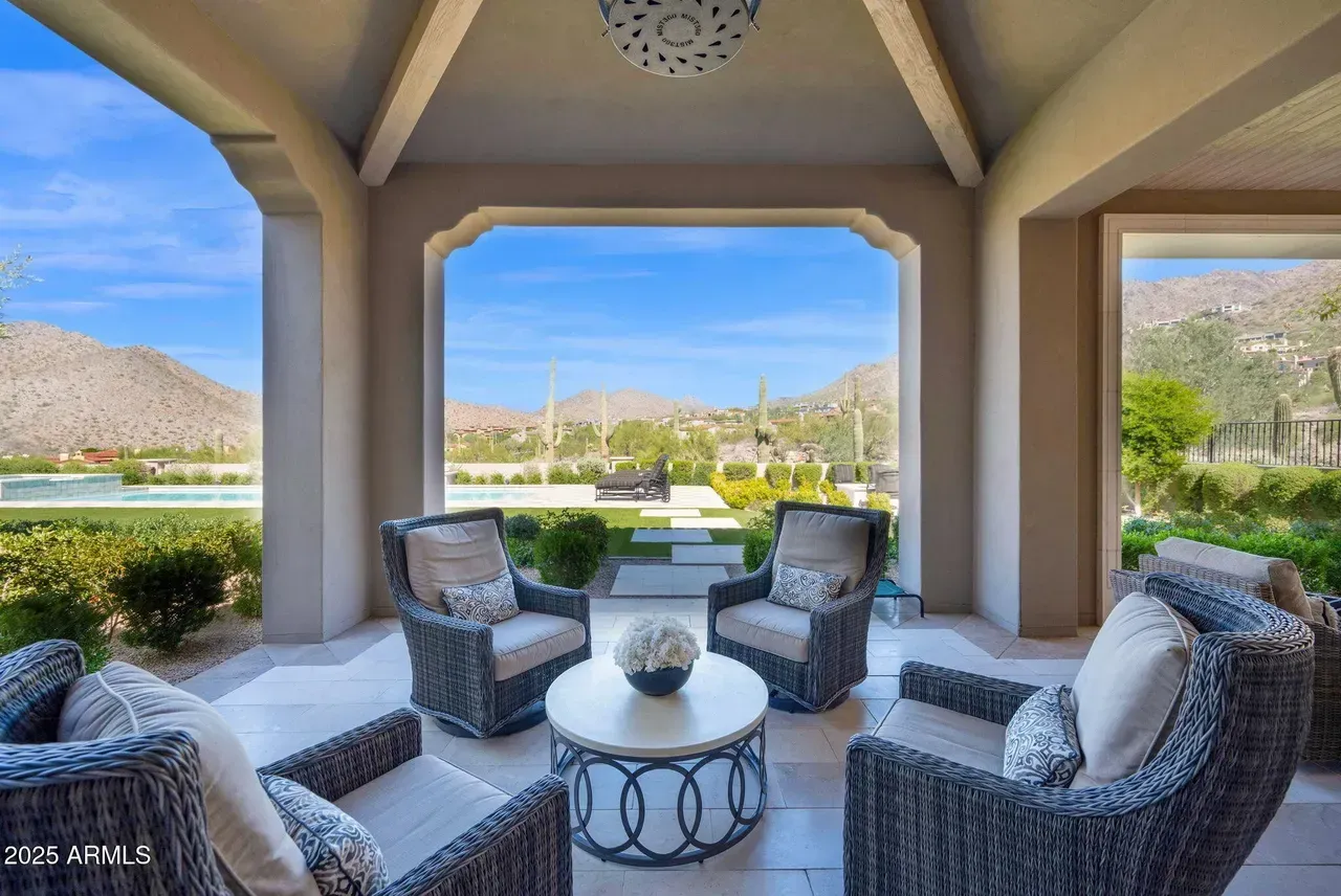 Patio with wicker chairs, round table, overlooking mountains and a golf course.