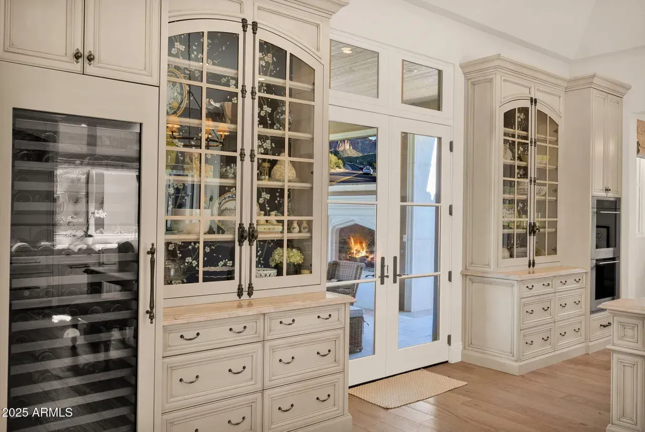 Elegant kitchen with glass-front cabinets, wine fridge, and double doors leading to a fireplace.