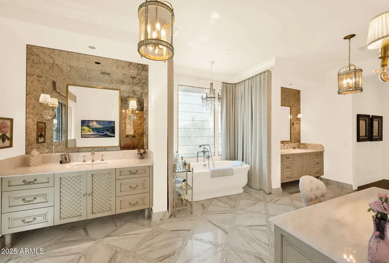 Luxurious bathroom with marble floors, a freestanding tub, and two vanities.