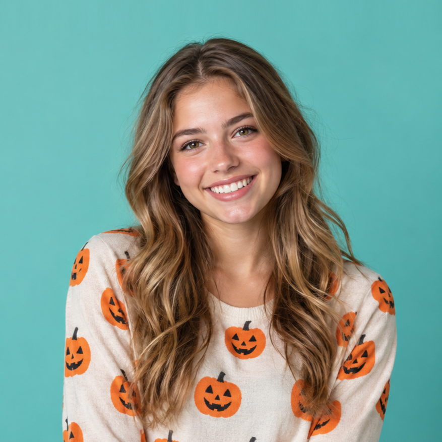 Smiling woman in a white shirt with orange jack-o'-lanterns on a teal background