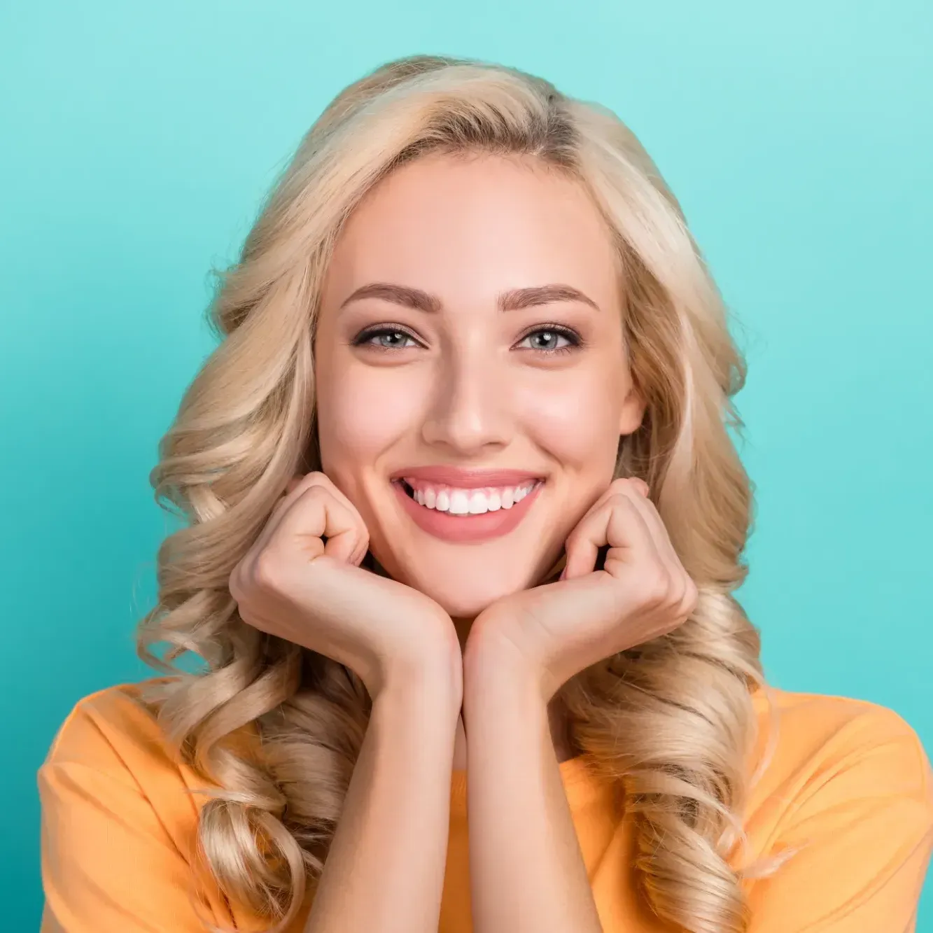 Blonde woman, with invisalign, resting chin on hands, smiling