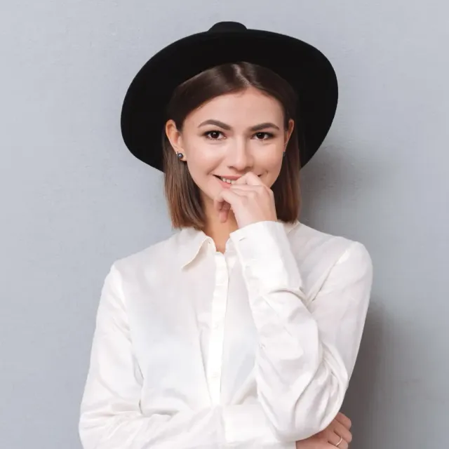 Woman wearing a hat, holding her hand over mouth