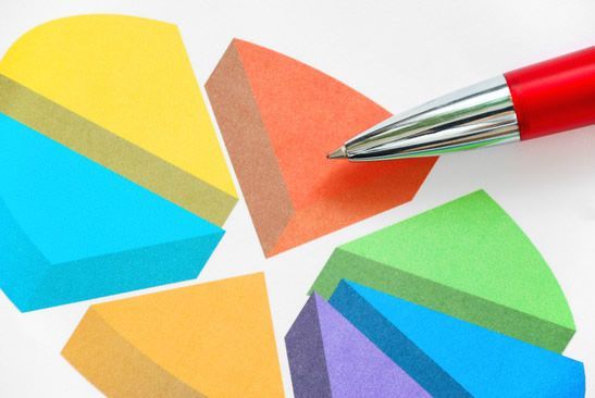 A pen is pointing at a pie chart on a piece of paper