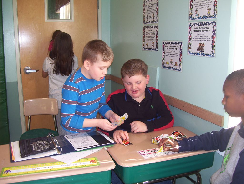 a group of young boys are sitting at desks in a classroom with posters on the wall.