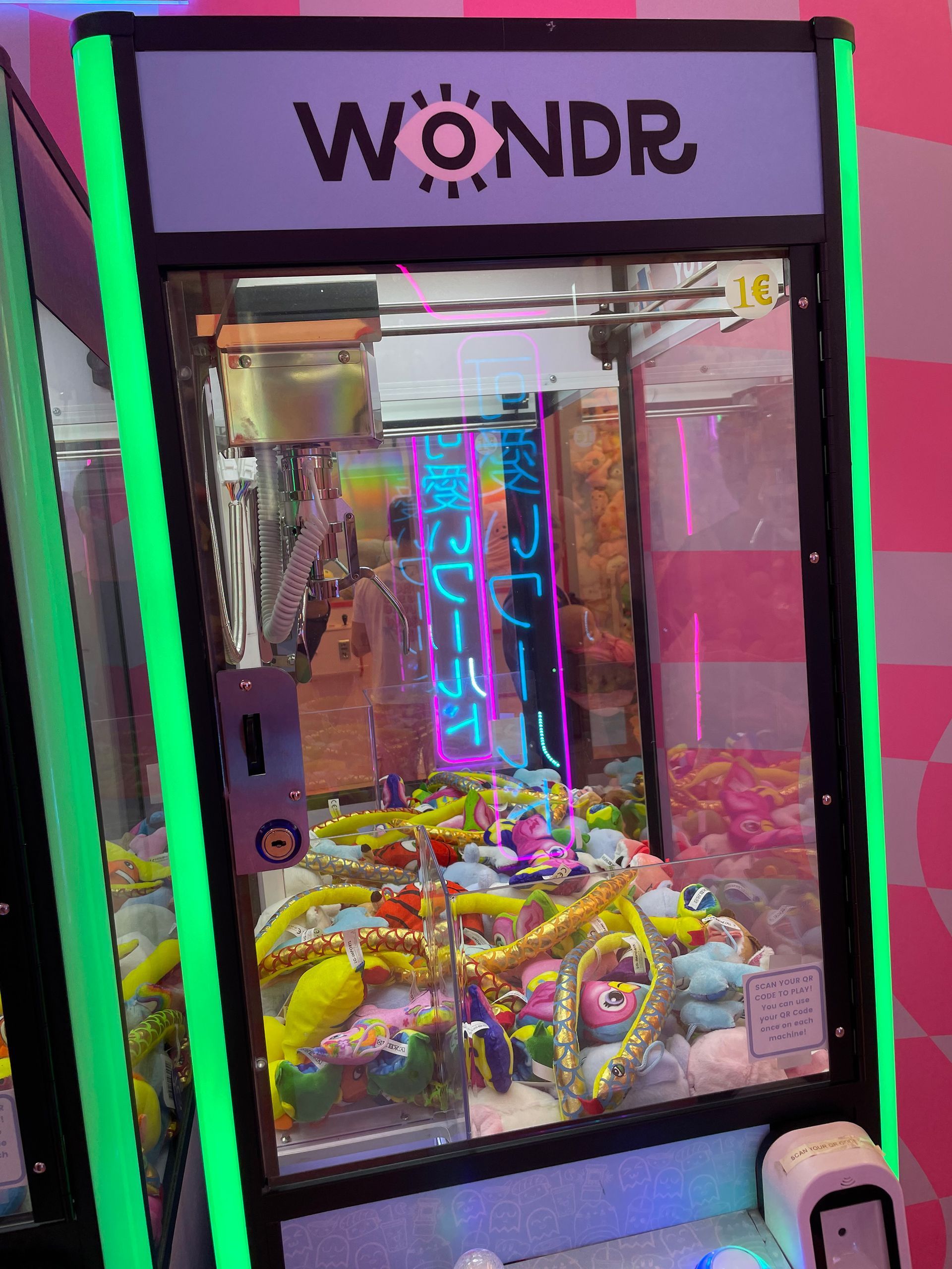 Grijpmachine met pluche speelgoed erin, neonreclame, zwart-groen frame.