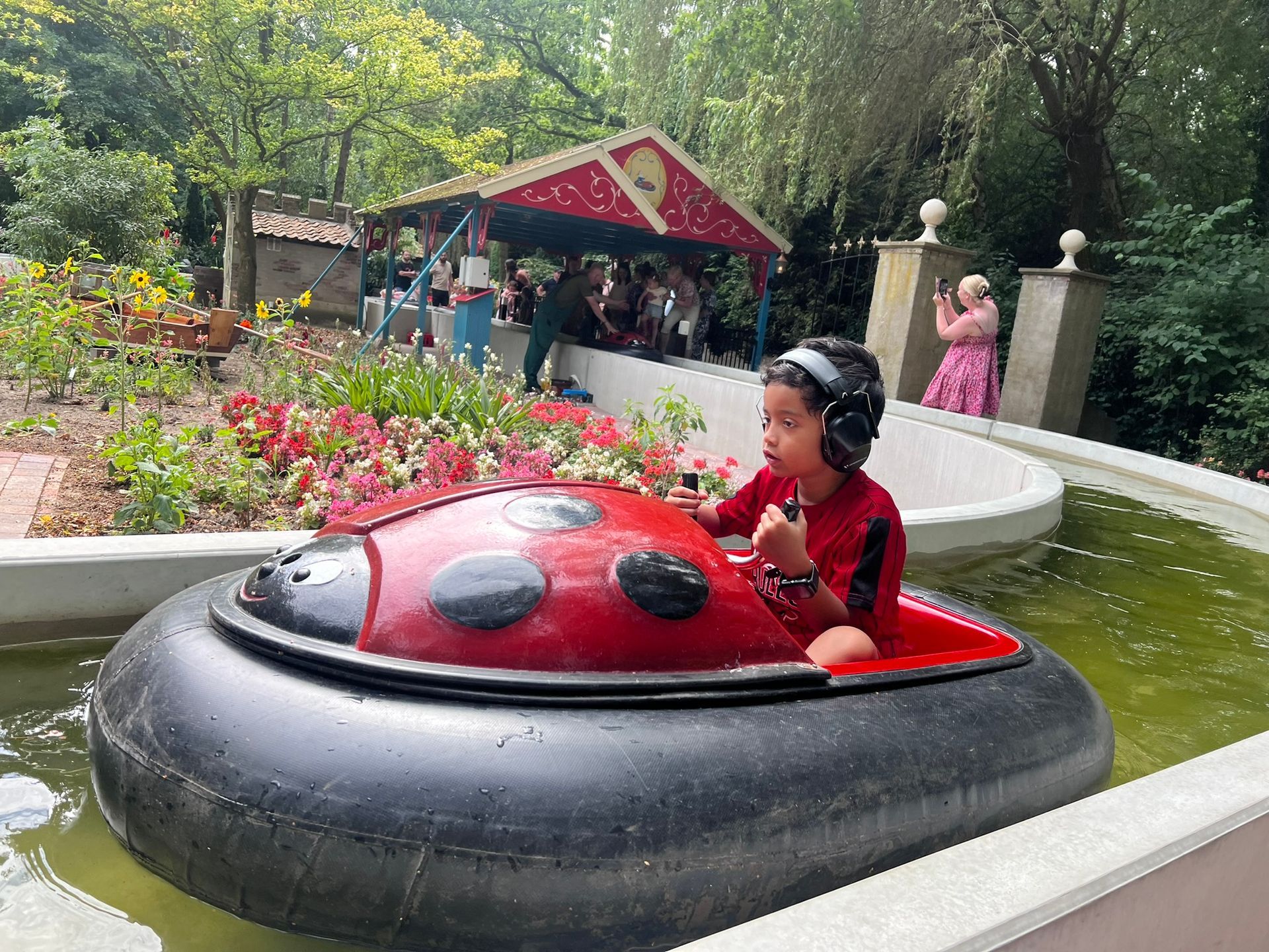 Kind in een rode lieveheersbeestjesboot op een waterattractie in een pretpark.