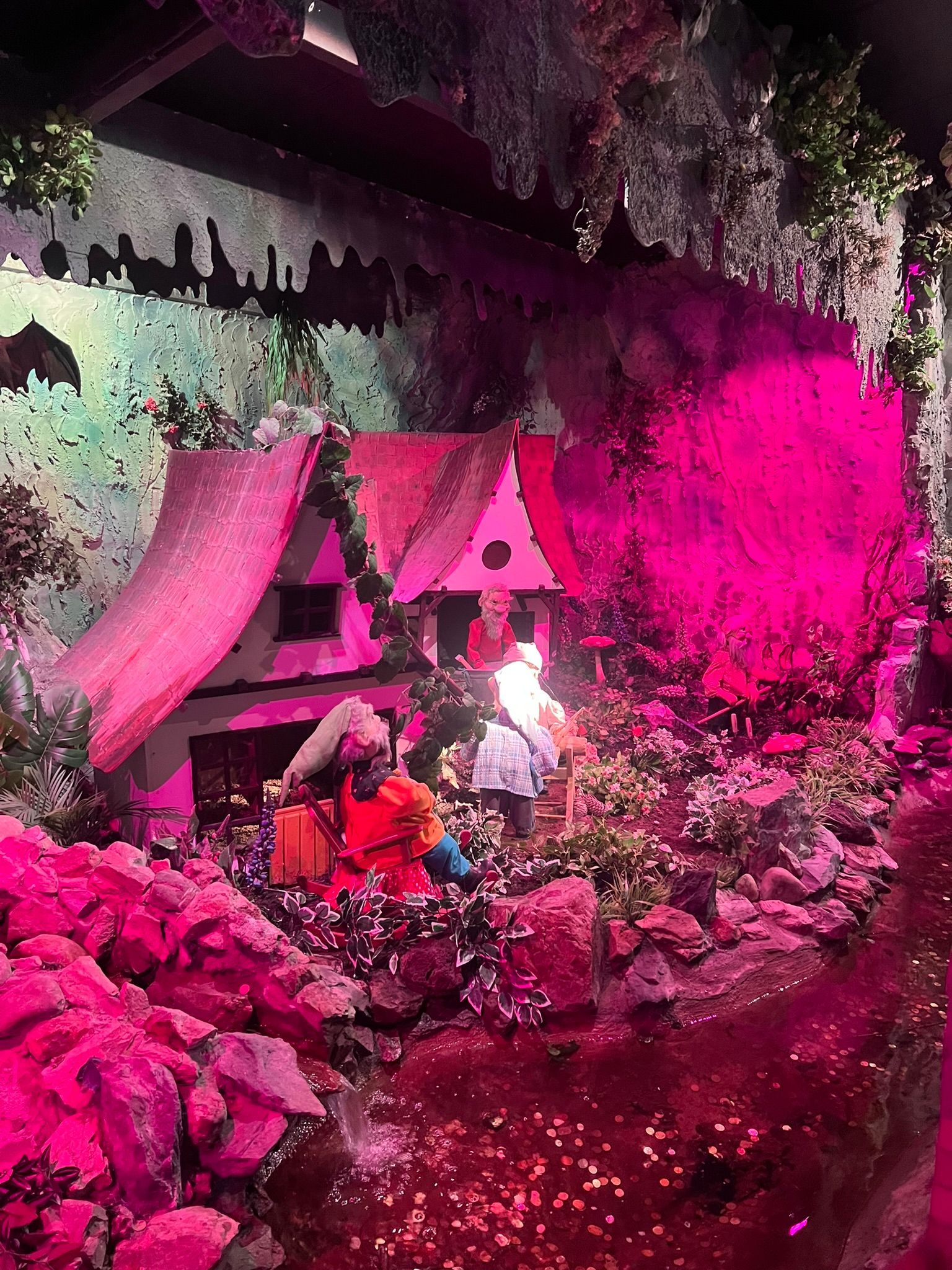Een miniatuur sprookjesachtig tafereel met een huisje, figuurtjes en roze verlichting.