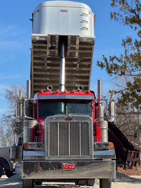 Red dump truck with raised bed, blue sky.