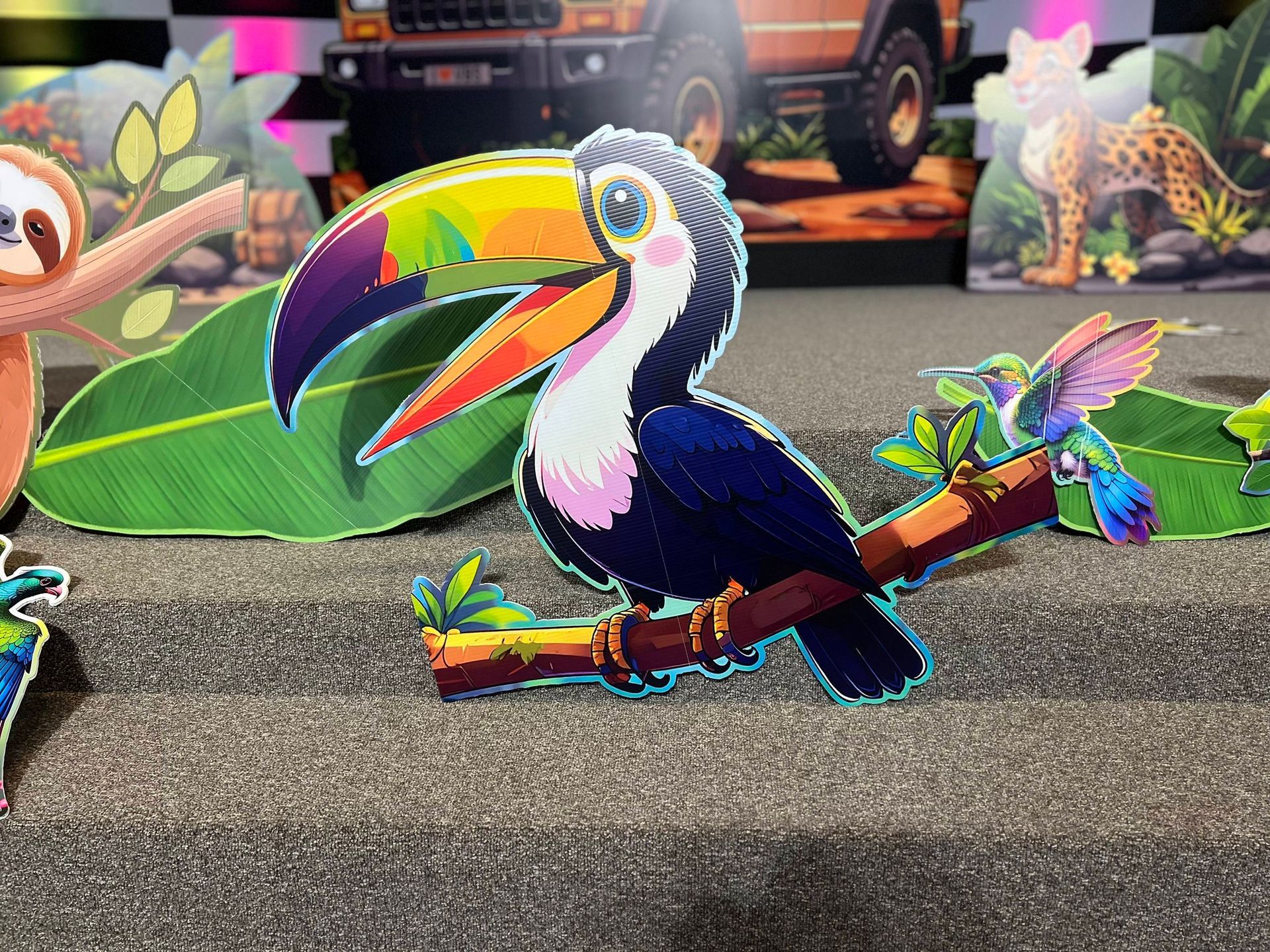 A colorful toucan bird sits on a branch with a small hummingbird; jungle scene.
