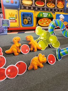A stage set with a cardboard cutout of a yellow Jeep, jungle-themed decorations, and a projector screen.