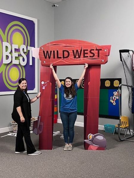 Two women stand with a cardboard