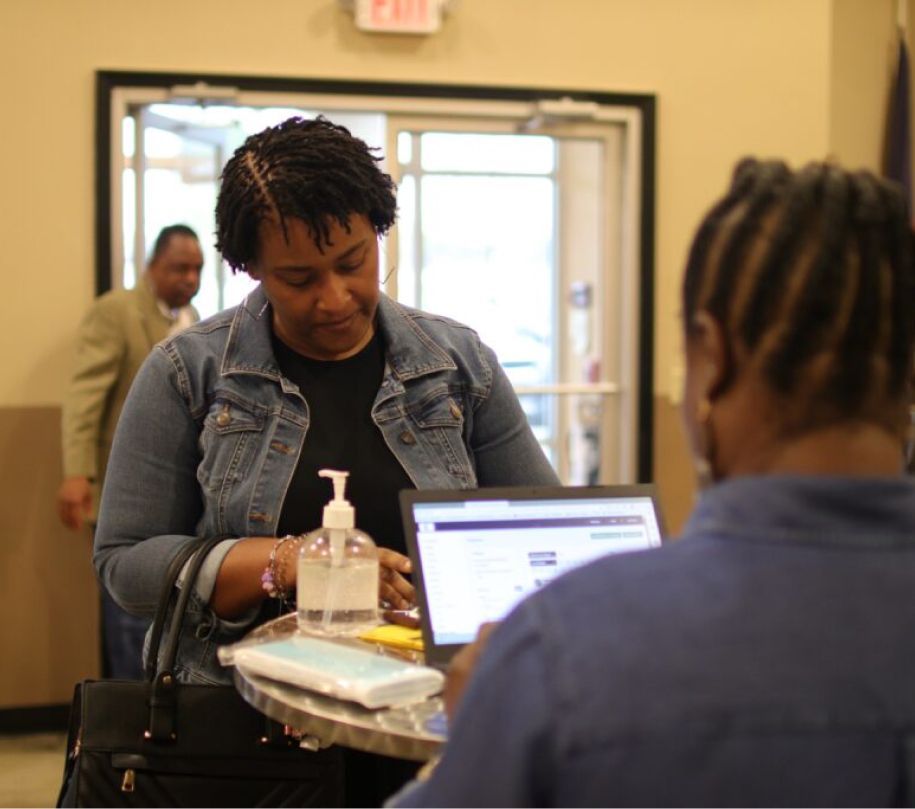 A woman in a denim jacket is using a laptop