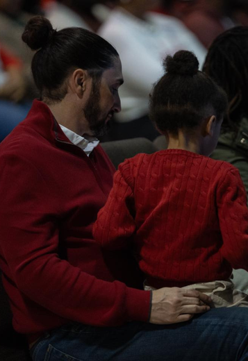 A man in a red sweater is holding a little girl in a red sweater