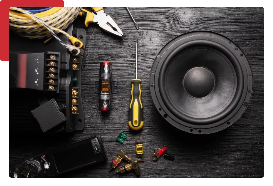 A speaker is sitting on top of a wooden table surrounded by tools.