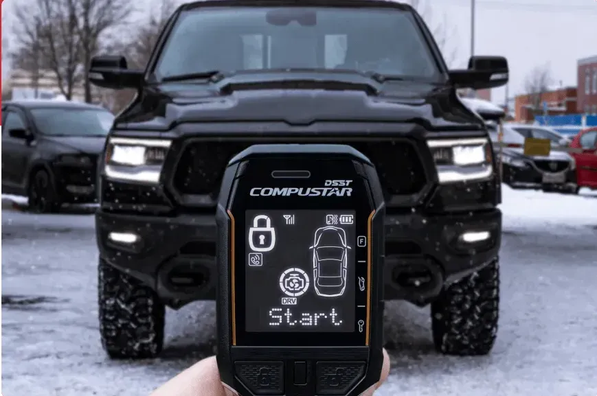 A person is holding a remote control in front of a black truck.