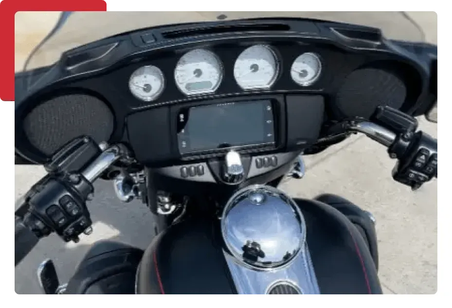 A close up of a motorcycle dashboard with a phone on it.