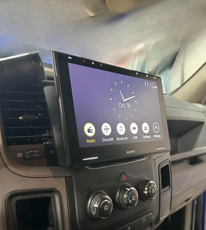 A clock on the dashboard of a car shows the time as 12:05