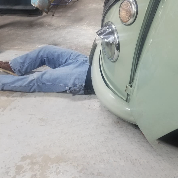A man laying on the ground next to a green car