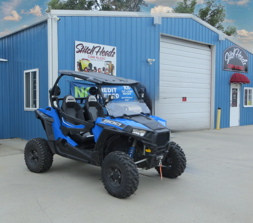 A blue atv is parked in front of a blue building