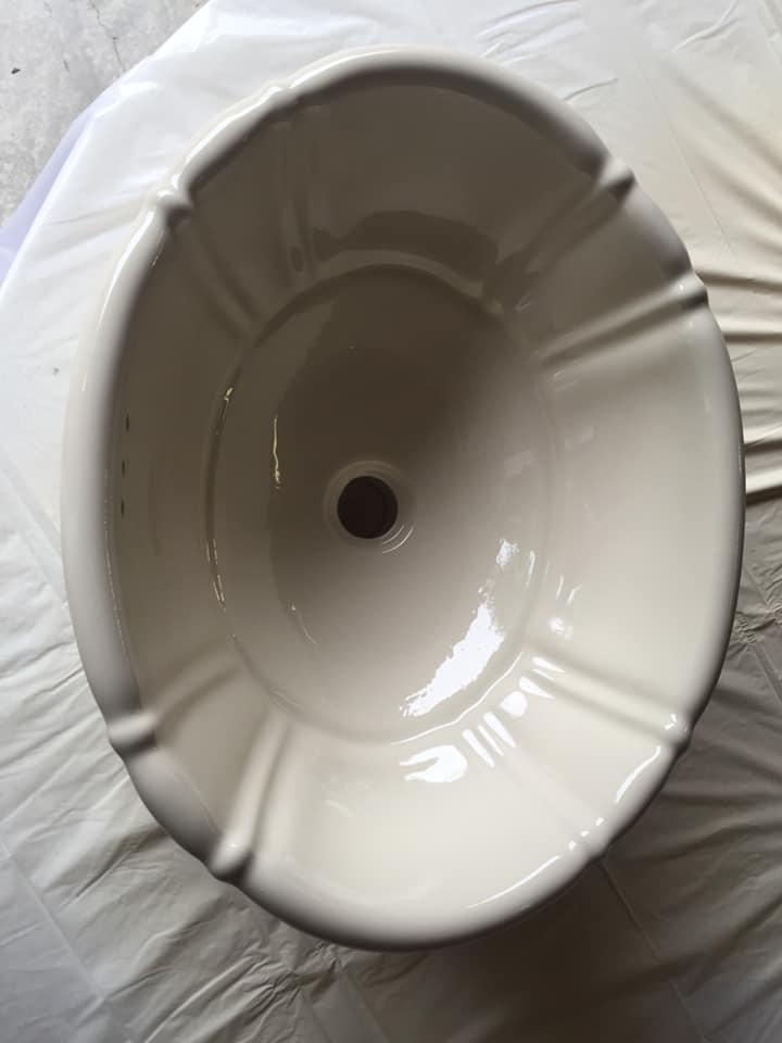 A white bowl with a hole in the middle is sitting on a table.