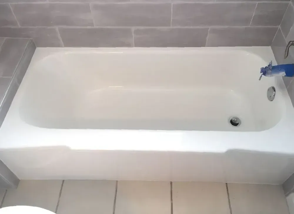 A white bathtub is sitting in a bathroom next to a toilet.