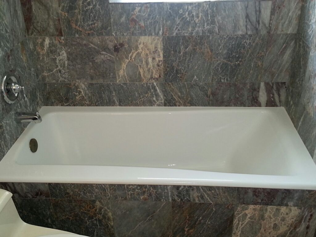 A bathtub is sitting in a bathroom next to a tiled wall.
