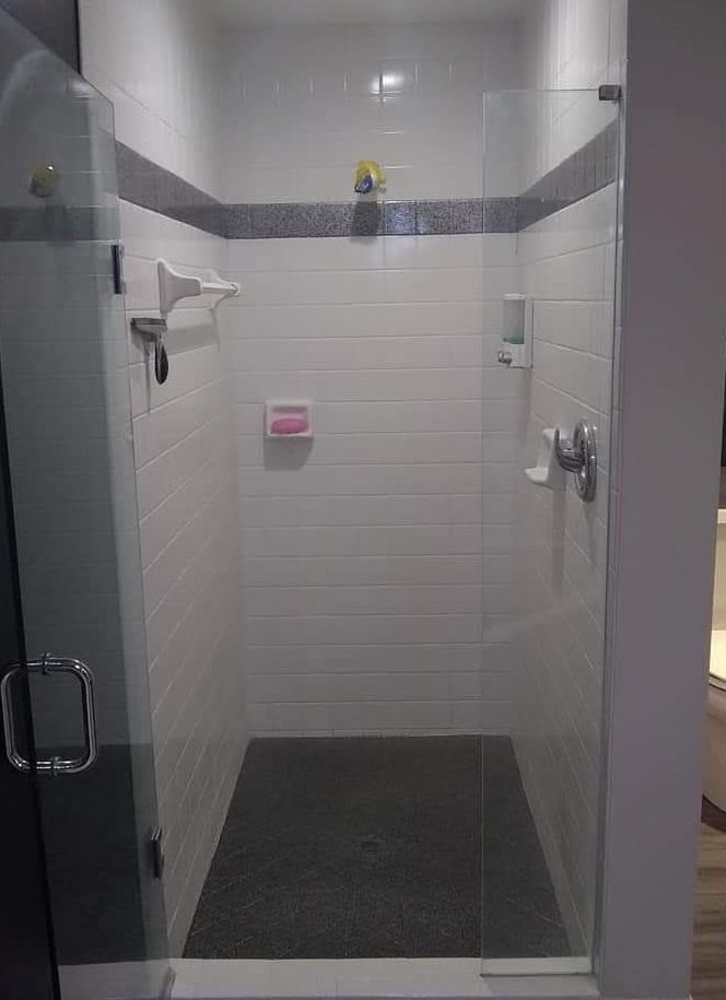 A bathroom with a walk in shower with a glass door.