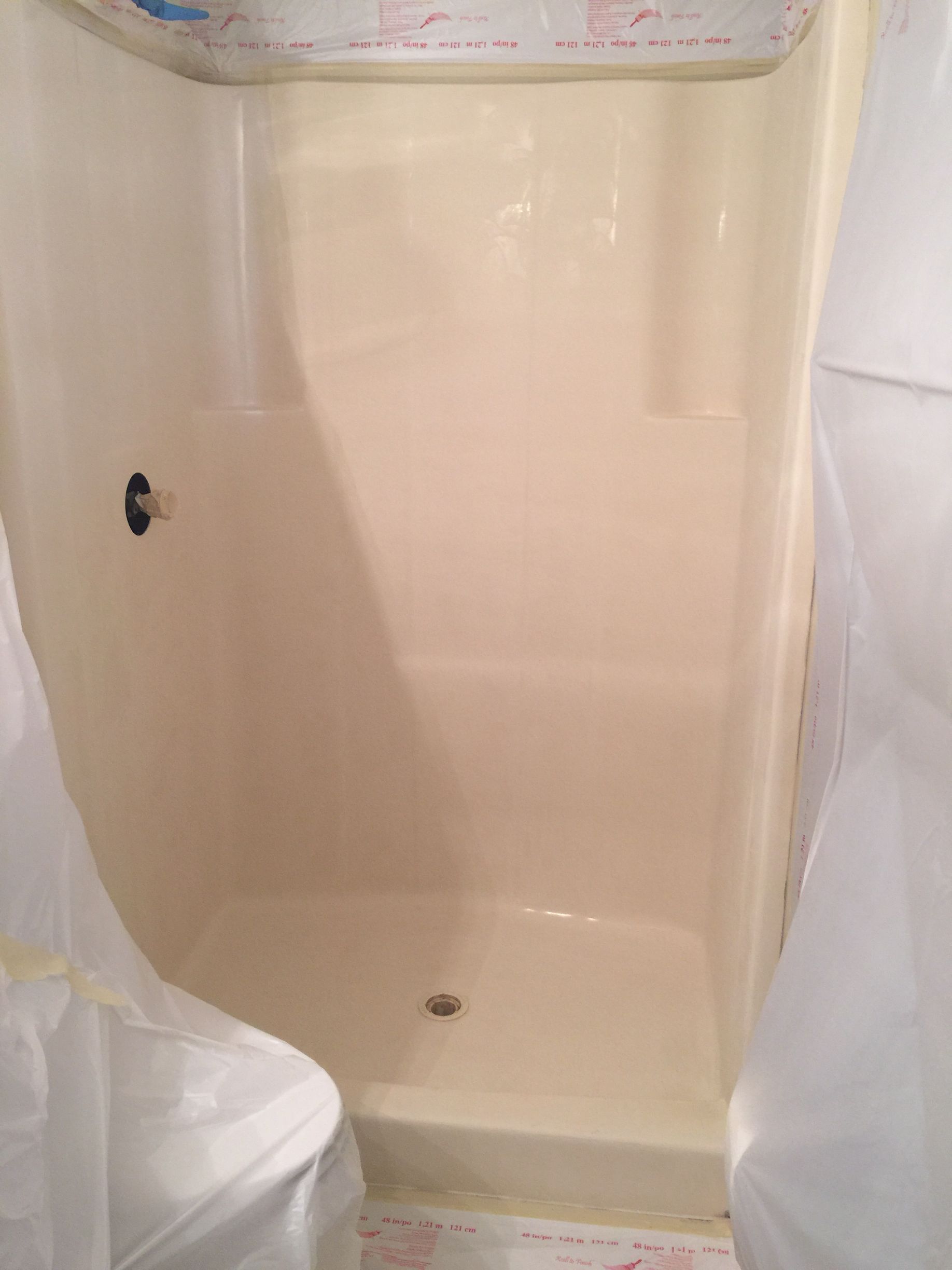A white shower stall in a bathroom with a white shower curtain.