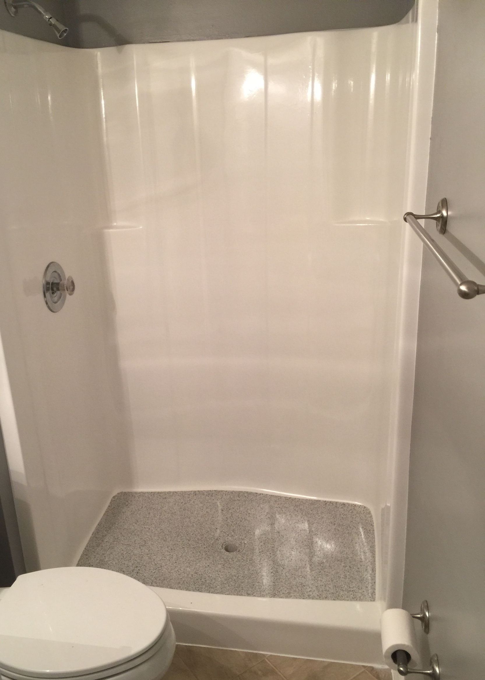 A bathroom with a toilet , shower , and towel rack.