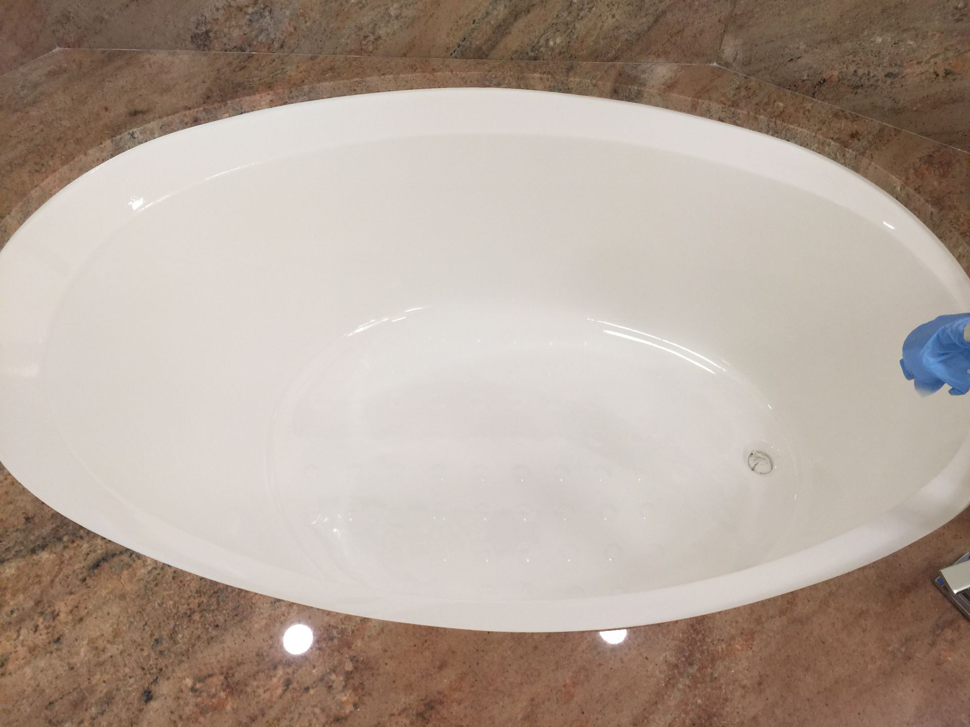 A white bathtub is sitting on top of a granite counter top.