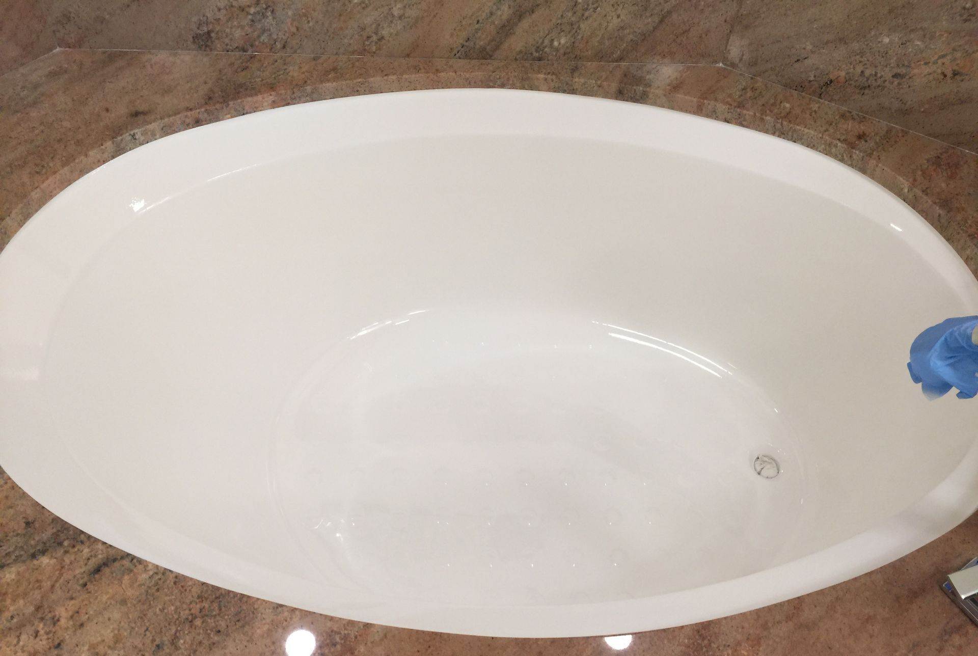 A white bathtub is sitting on top of a granite counter top.