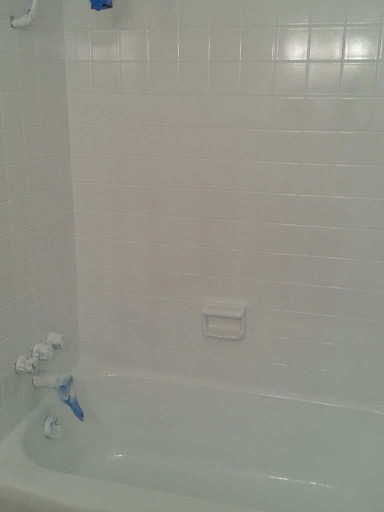 There is a bathtub in the bathroom with white tiles.