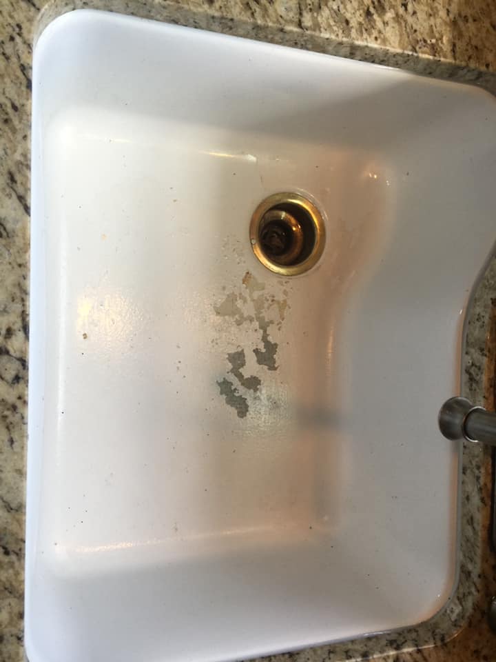 A white kitchen sink is sitting on top of a granite counter.