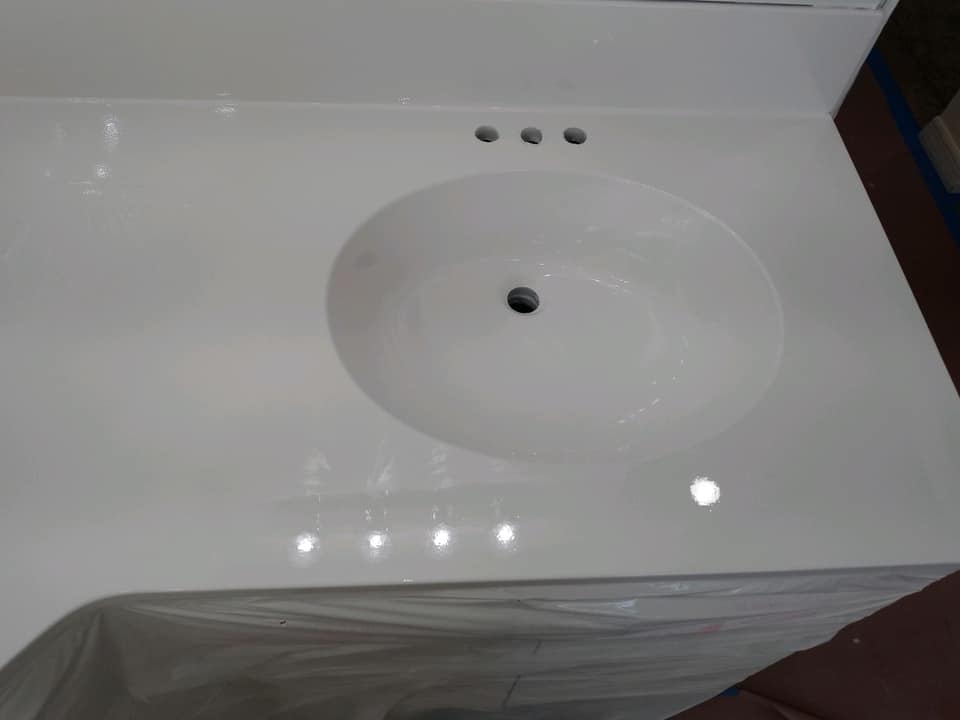 A white bathroom vanity with a round sink and three faucets.