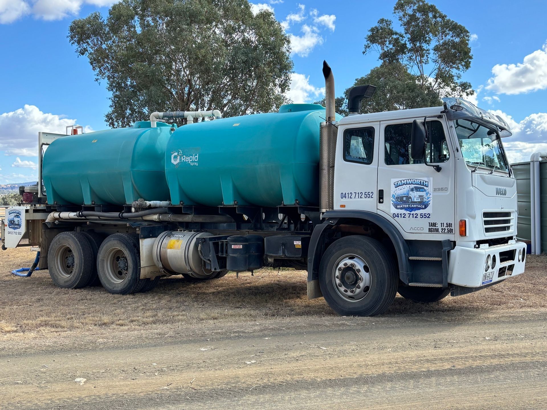 An Orange Tanker Truck Sprays Water Onto a Dirt Road — Tamworth Water Cartage in Duri, NSW