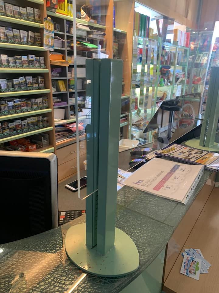 Barriera protettiva trasparente in acrilico su un bancone cassa di un minimarket.
