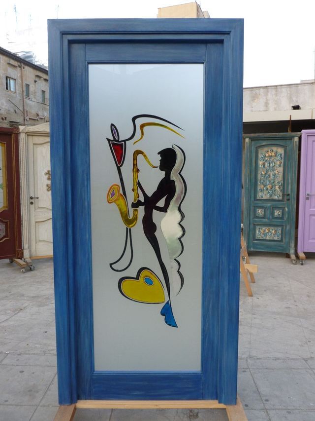 Cabina telefonica con cornice blu e figura astratta dipinta sul vetro, situata all'aperto.