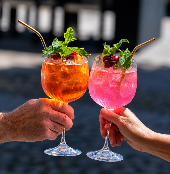 Due cocktail all'arancia su un tavolo con vista sul lago e sulle montagne al tramonto.