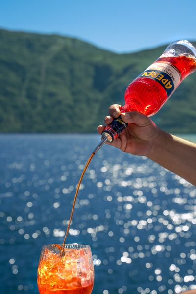 Quattro cocktail Aperol Spritz con fette d'arancia, su un bancone del bar.