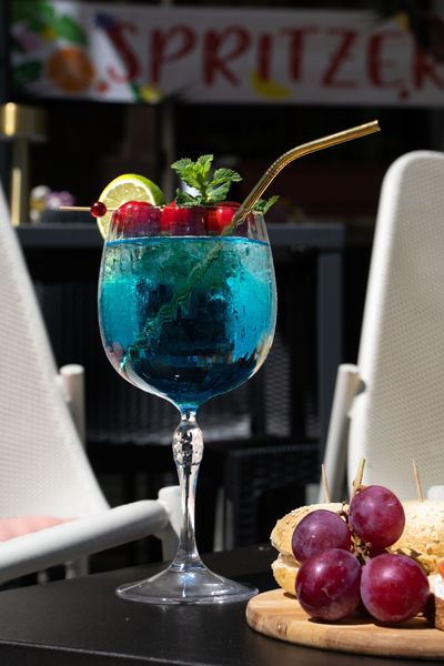 Cocktail rosso con una fetta d'arancia su un tavolo di un ristorante, sfondo sfocato con luce calda.