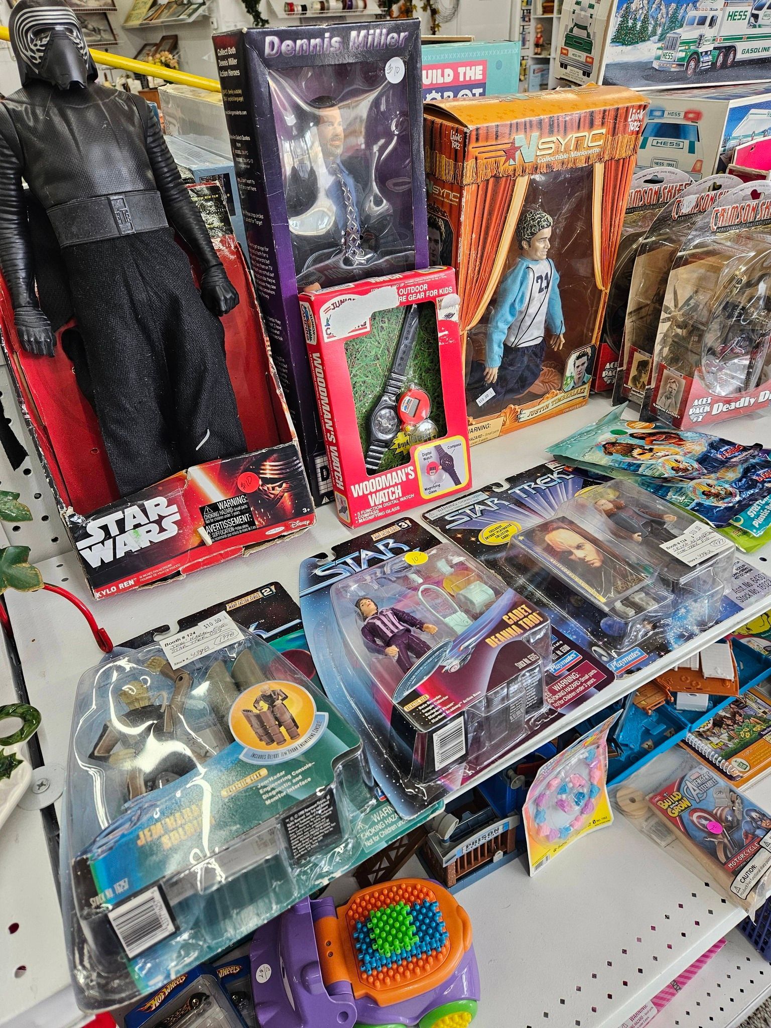 Toy aisle with action figures and playsets on a store shelf, including black, orange, and blue packaging.