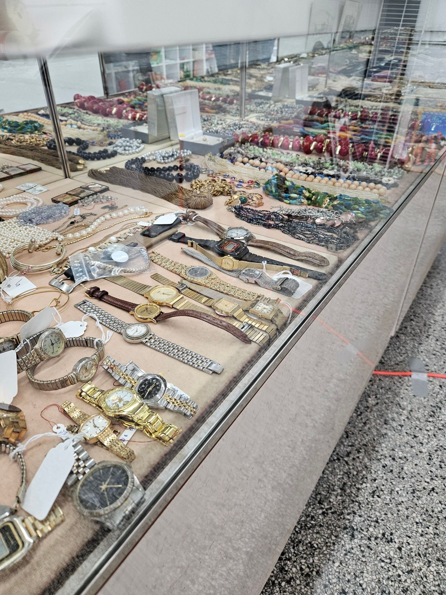 Jewelry display case with rows of watches and bracelets under glass in a store