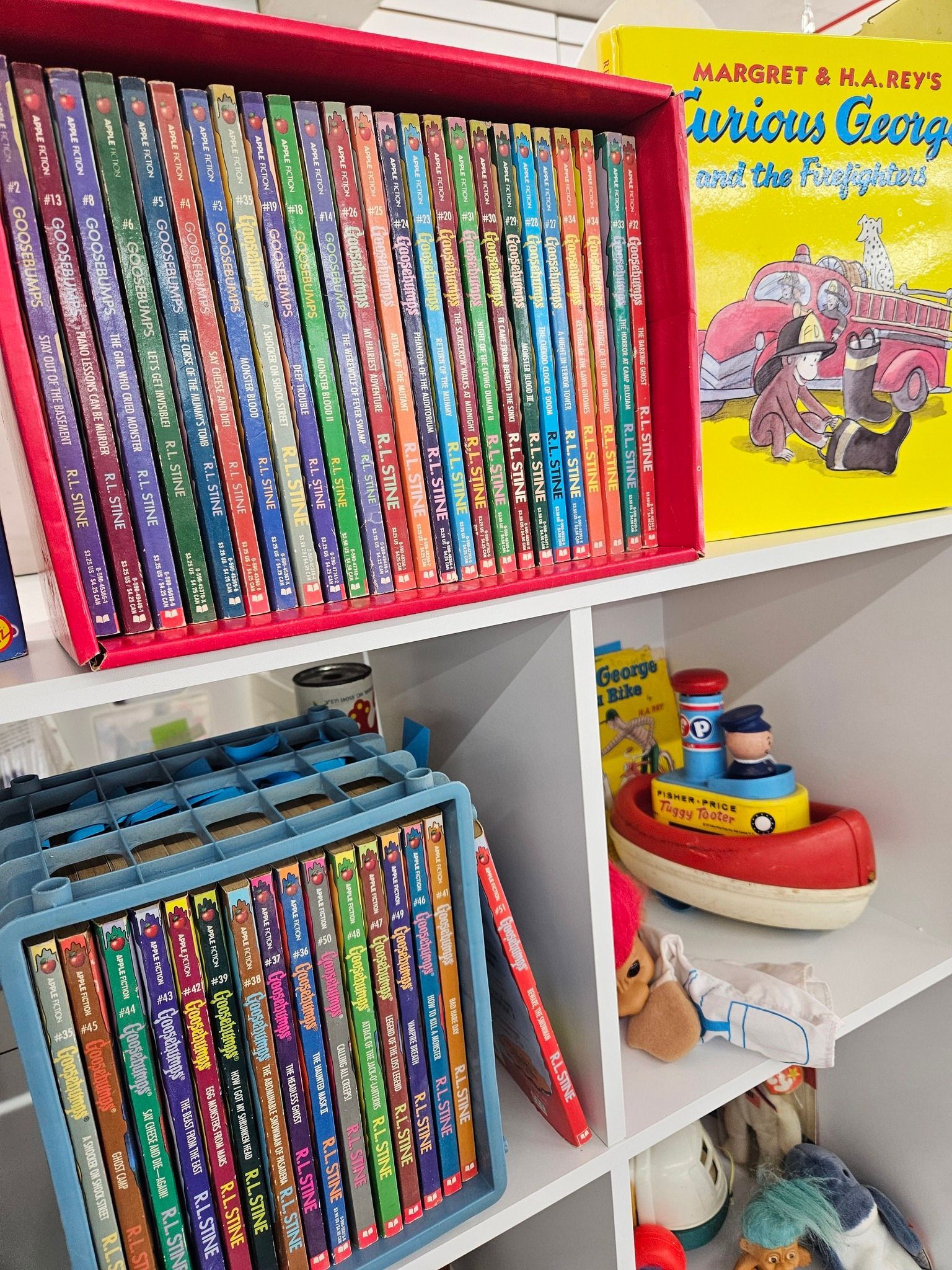 Children’s books and toys arranged on white shelves, including colorful book spines and a yellow Martha Speaks book cover