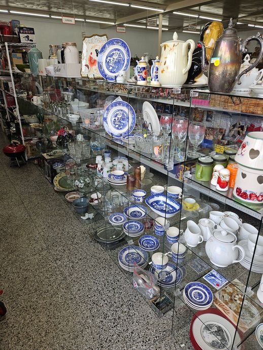 Shelves of blue-and-white ceramic dishes and teapots in a thrift shop aisle