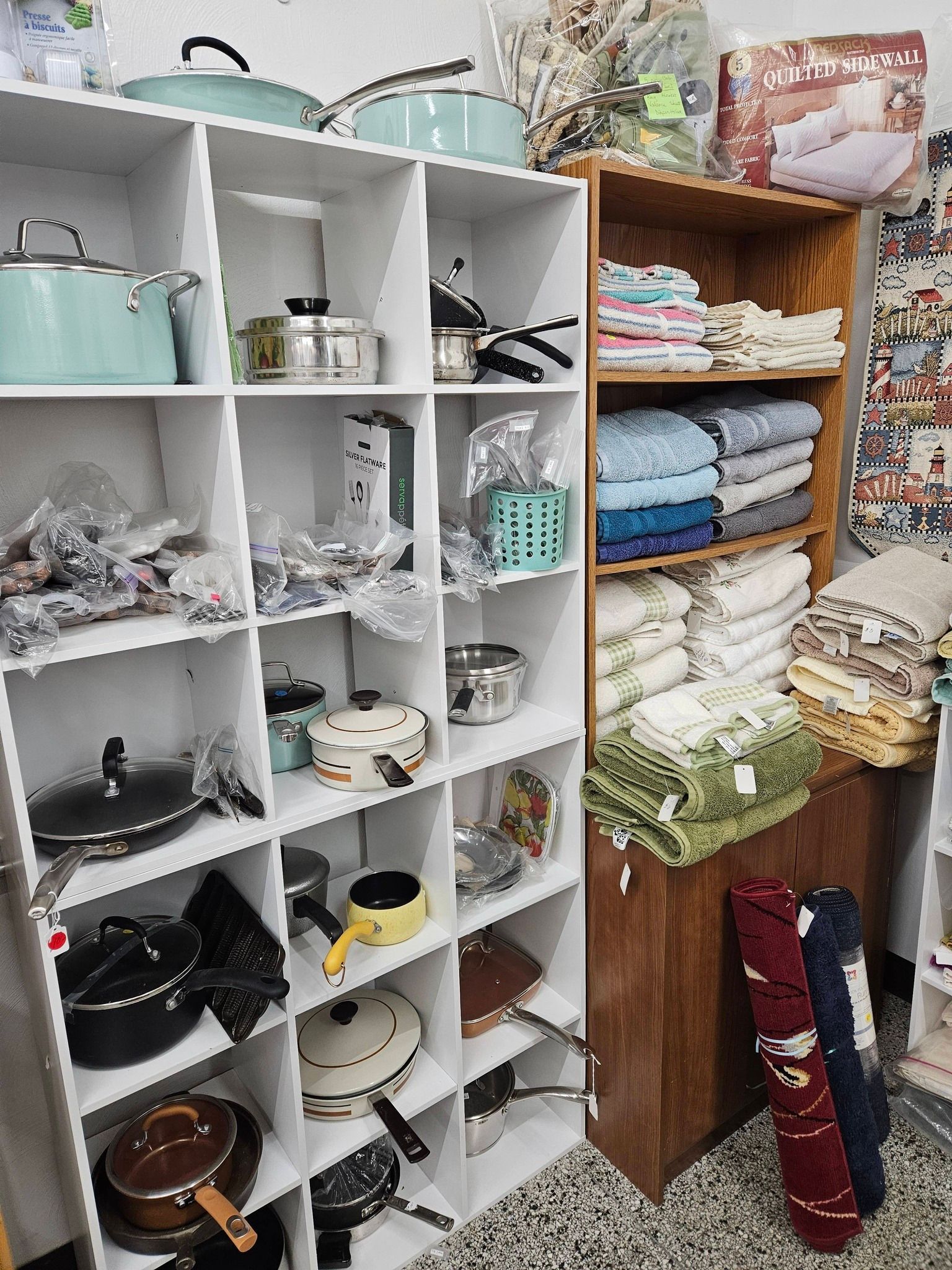 Shelves stocked with yarn, fabric, craft supplies, and kitchenware in a small shop or storage room
