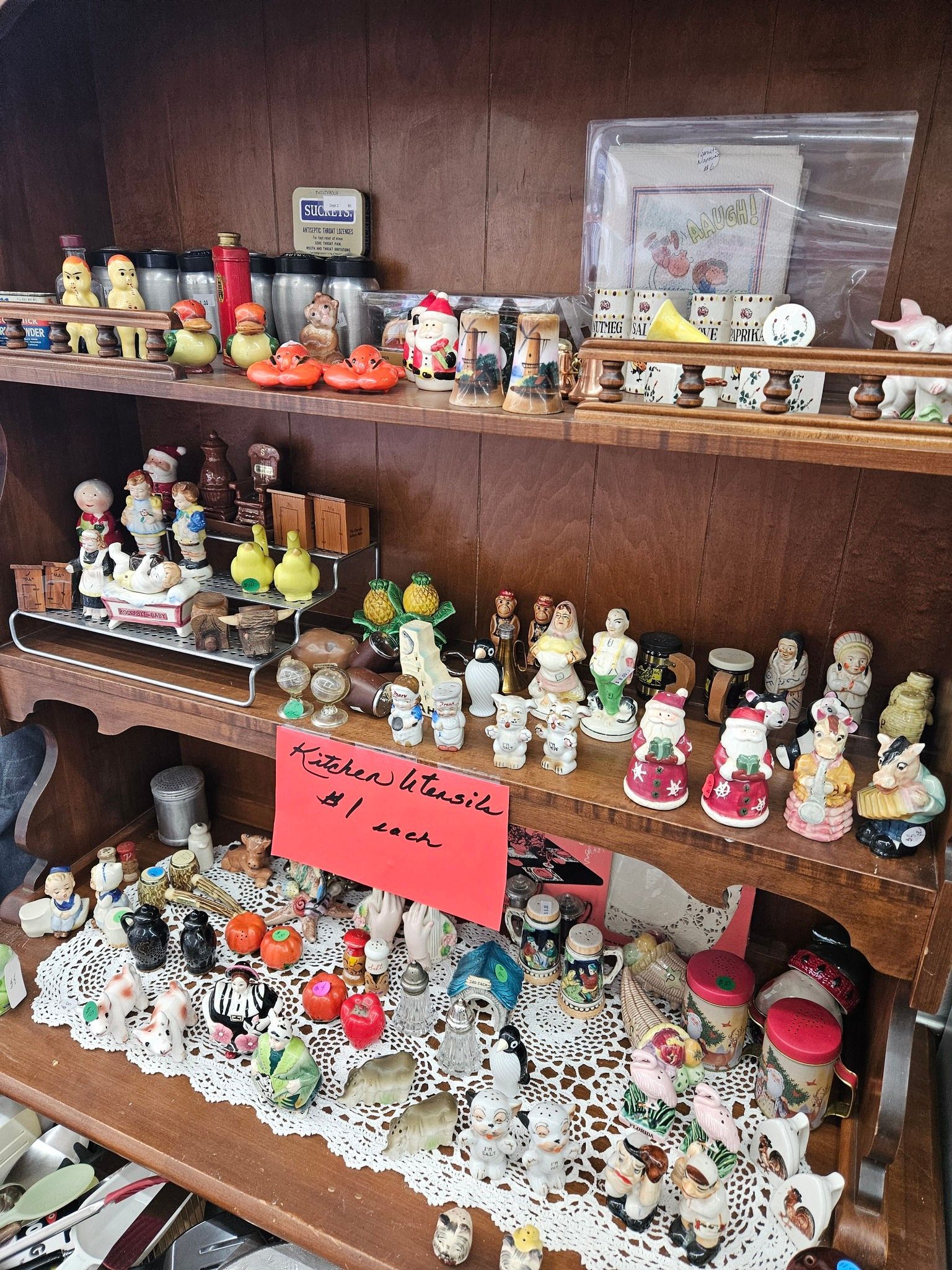 Shelves crowded with colorful miniature figurines and small dolls, with a red price sign in front.